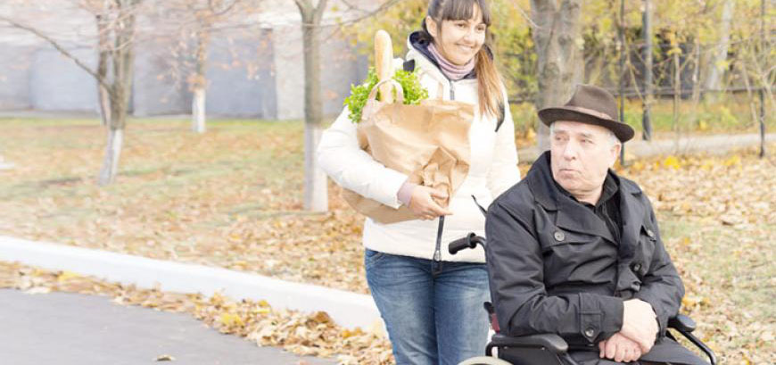 Woman walking with man in wheelchair